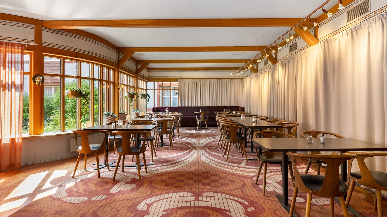 En del av restaurangen Broken Dreams i Borlänge med träbord, trästolar, och heltäckningsmatta.