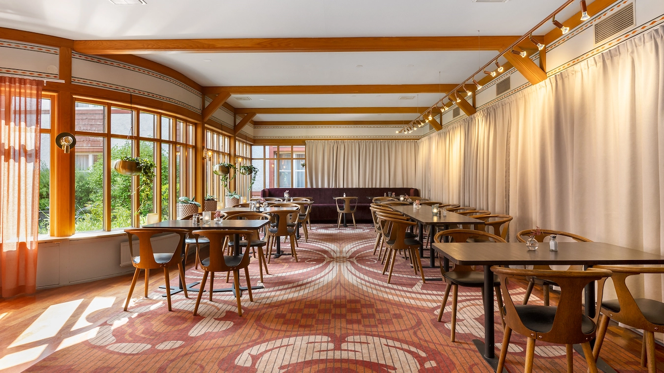 En del av restaurangen Broken Dreams i Borlänge med träbord, trästolar, och heltäckningsmatta.