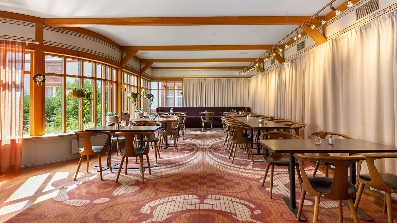 En del av restaurangen Broken Dreams i Borlänge med träbord, trästolar, och heltäckningsmatta.