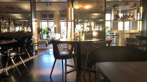 En tom restaurang. Bord och stolar. En bardisk i bakgrunden.