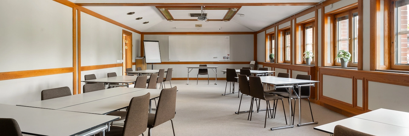 En bild av konferenslokalen Jussi Björling på Best Western Gustaf Wasa Hotel i Borlänge. Många sittgrupper med tillhörande bord i en stor lokal. En whiteboardtavla och projektor syns i bakgrunden.