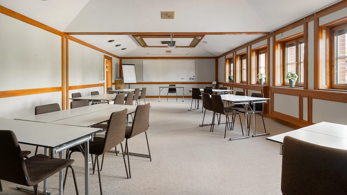 En bild av konferenslokalen Jussi Björling på Best Western Gustaf Wasa Hotel i Borlänge. Många sittgrupper med tillhörande bord i en stor lokal. En whiteboardtavla och projektor syns i bakgrunden.