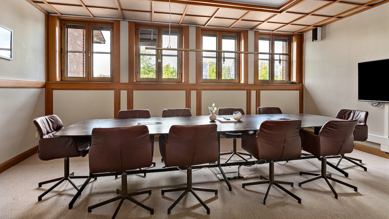 En bild av Styrelserummet på Best Western Gustaf Wasa Hotel i Borlänge. 10 skinnstolar runt ett avlångt träbord med en tv på ena väggen.