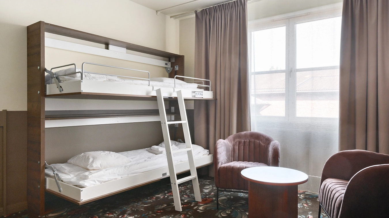 En utfälld våningssäng vid en sittgrupp. Ett stort fönster i bakgrunden.