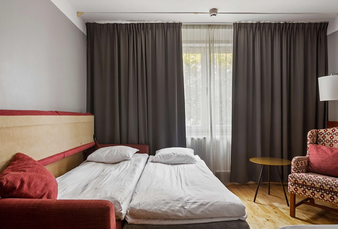 En utfälld bäddsoffa, en fåtölj, och ett litet bord vid ett par fönster.