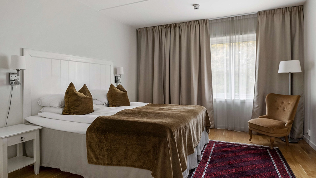 Ett Superior dubbelrum på Best Western Gustaf Wasa Hotel i Borlänge med rymlig säng, en fåtölj, och stora fönster. 