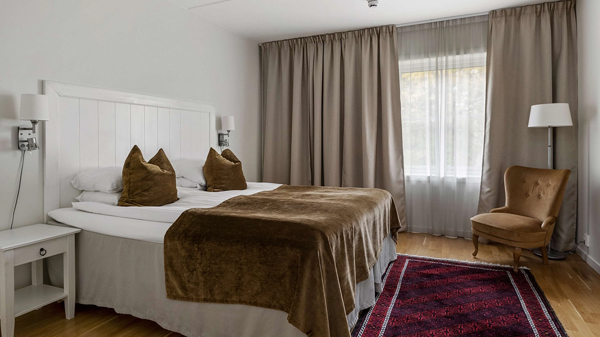 Ett Superior dubbelrum på Best Western Gustaf Wasa Hotel i Borlänge med rymlig säng, en fåtölj, och stora fönster. 