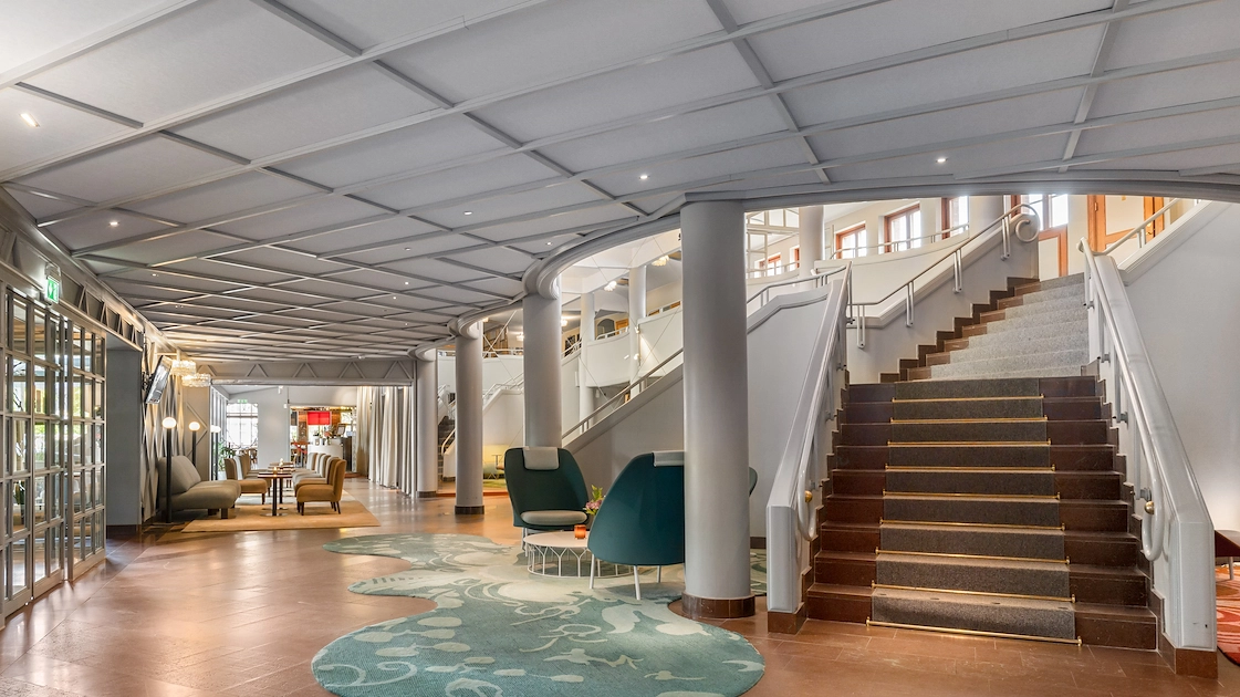 En del av den eleganta hotellobbyn på Best Western Gustaf Wasa Hotel med vitt tak, vita pelare, och moderna sittgrupper.