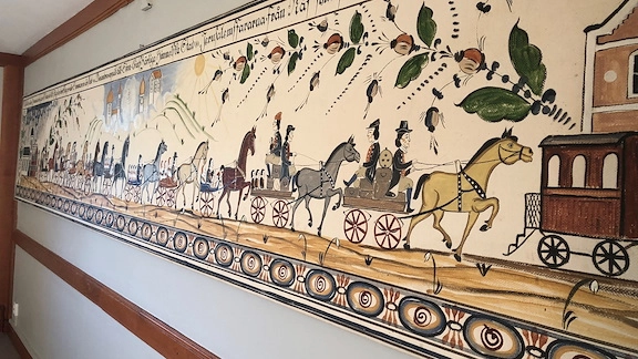 En tavla med hästar som drar vagnar i led.