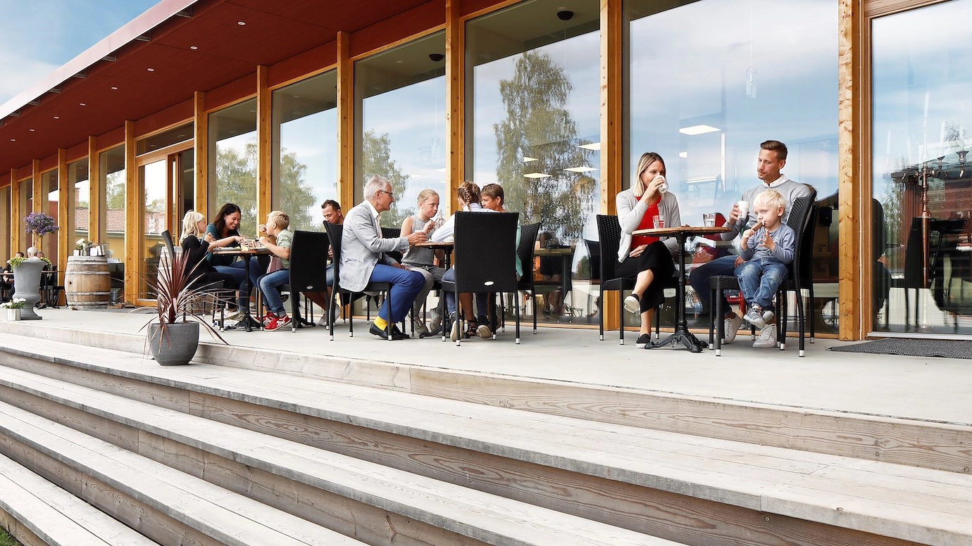 Ett utomhuscafé vid en trappa. Flera människor sitter och fikar.