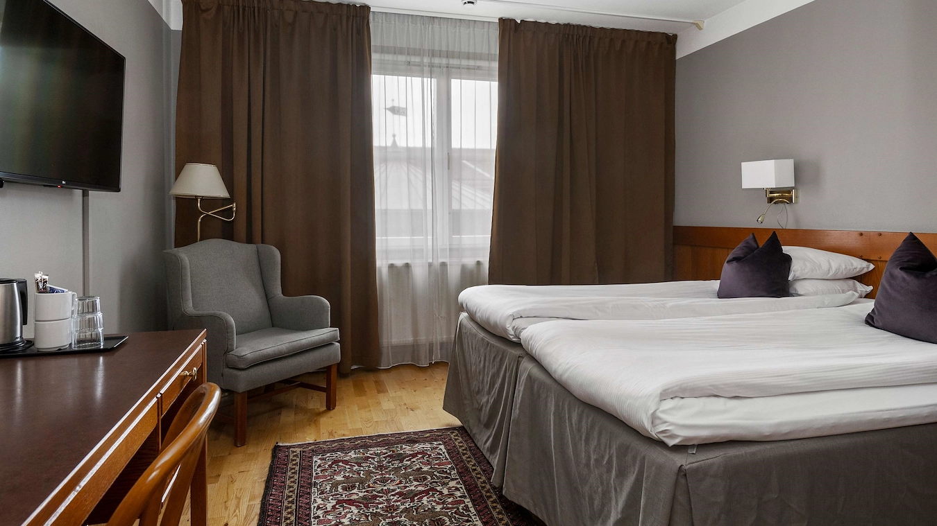 Ett standardrum på Best Western Gustaf Wasa Hotel i Borlänge med twinsängar, en fåtölj, och stora fönster. 