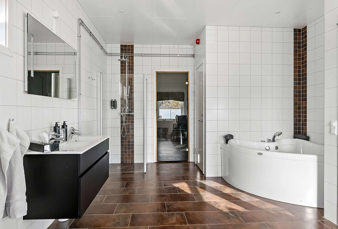 Ett badrum med ett stort handfat, en dusch, och ett bubbelbad/badkar.